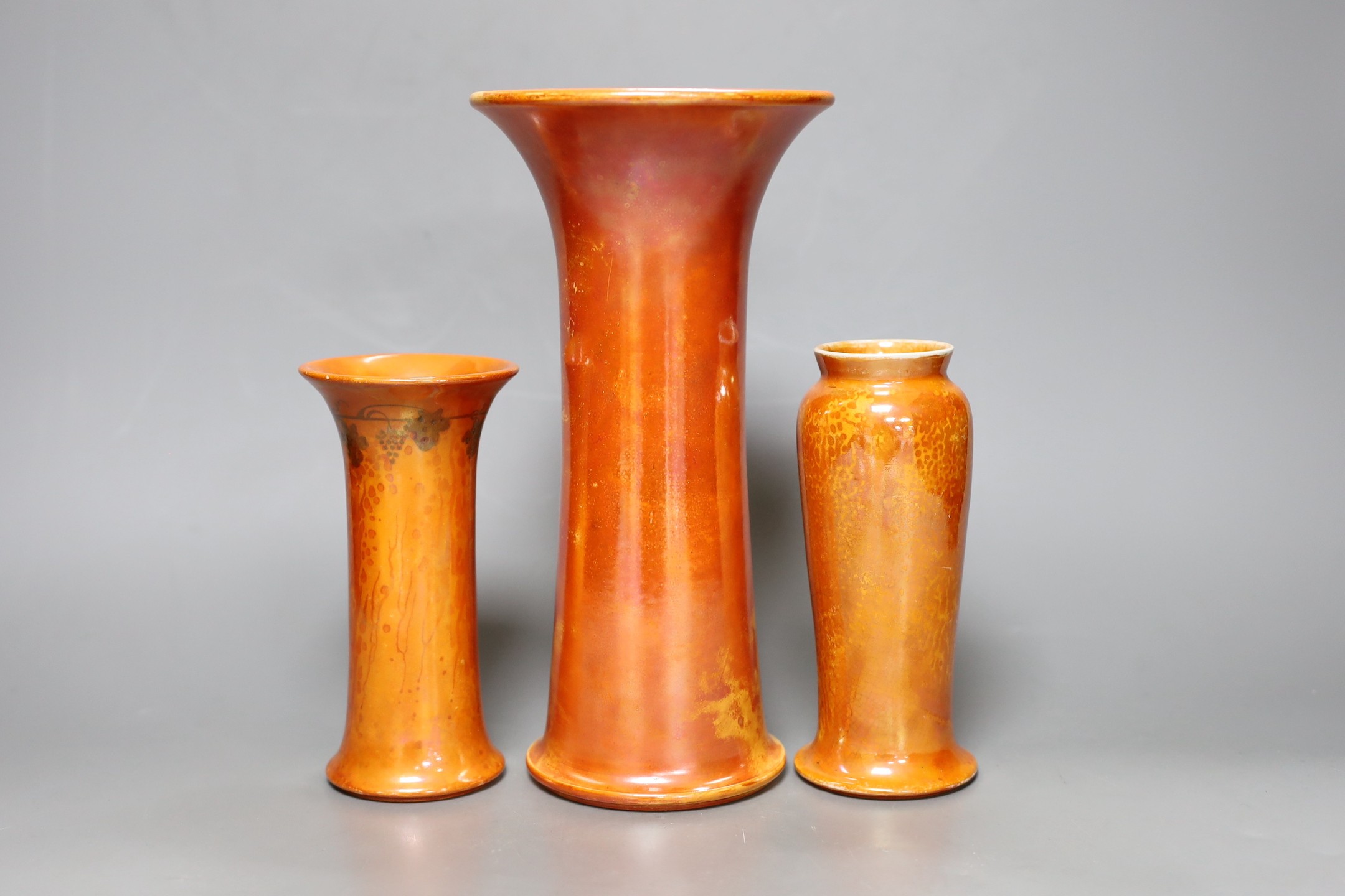 A group of three Ruskin orange lustre vases, largest 25cm